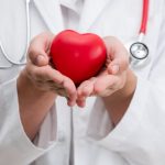 Doctor holding a red heart at hospital office. Medical health care and doctor staff service concept.